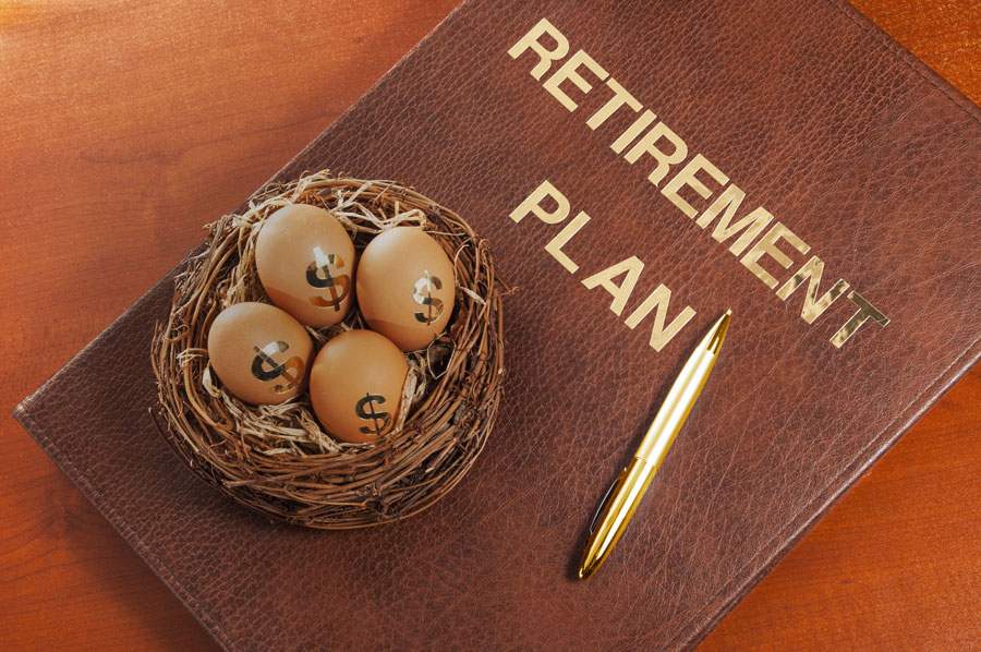 A leather-bound book labeled “RETIREMENT PLAN” with a basket of eggs and a pen.
