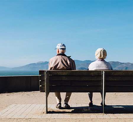 older couple sitting on bench looking at mountains